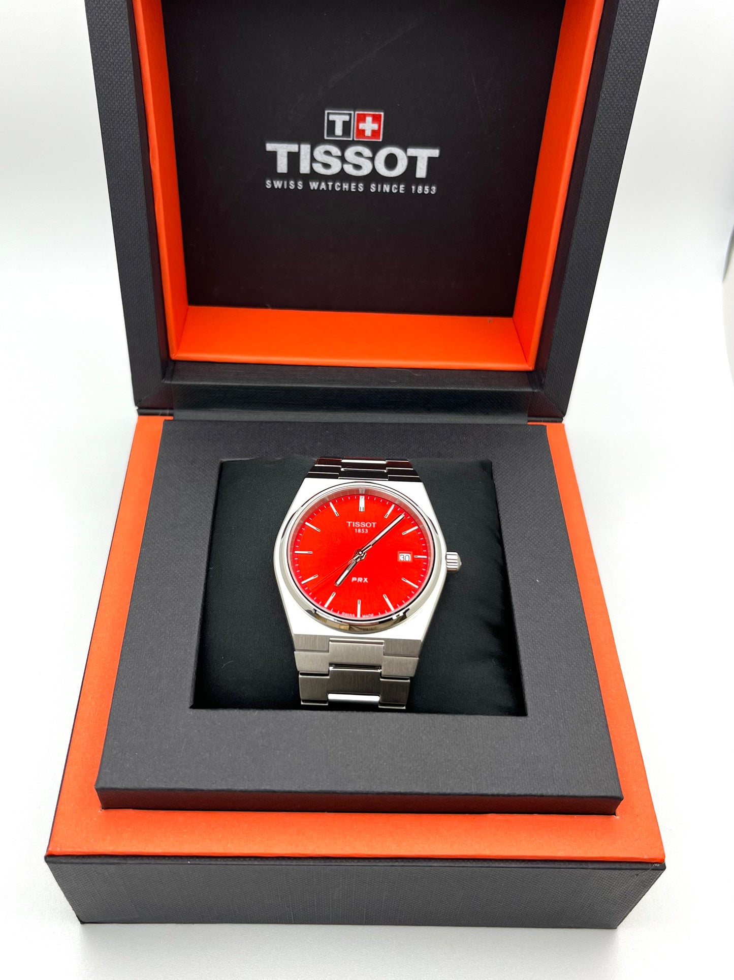 Tissot PRX Quartz T137.410.11.421.00 40mm stainless steel men’s watch with red dial, date display, sapphire crystal, and 100m water resistance
